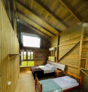 a room with two beds in a wooden cabin at Pousada Vale da Magia in Praia do Rosa