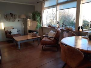 uma sala de estar com cadeiras, uma mesa e janelas em De Jutter, in natuurgebied en vlakbij het Strand em Callantsoog