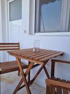 a wooden picnic table with two chairs and a window at Tolo at sea - Nova in Tolo
