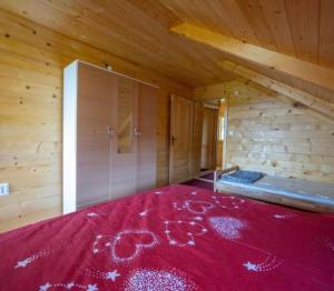 1 dormitorio con 1 cama roja en una cabaña de madera en Vikendica Kameno, en Kameno