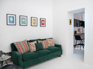 Pescheria Industriale في ريبوستو: أريكة خضراء في غرفة معيشة مع صور على الحائط