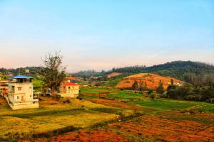 a view of a field with houses and a hill at Ooty AR Residency in Ooty