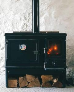 een zwarte kachel met een vuur erin bij Beatshach Bothy - Speyside, Incredible location! in Dufftown