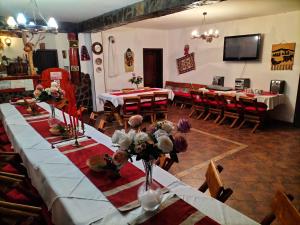 une salle à manger avec des tables, des chaises et une télévision dans l'établissement Vila Rina, à Moieciu de Sus