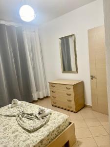 een slaapkamer met een bed, een dressoir en een spiegel bij Beach Apartments Durres in Durrës