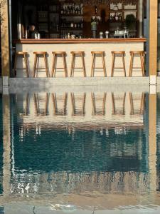una fila de taburetes frente a una piscina de agua en Ikaros Suites en Amoudara Herakliou