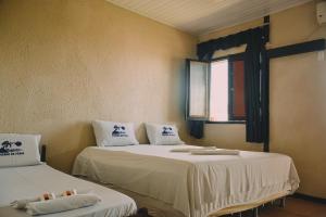 two beds in a room with a window at A Pousada da Praia in São Luís