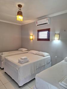 a bedroom with two beds and a window at Pousada Grand Fortim in Camocim
