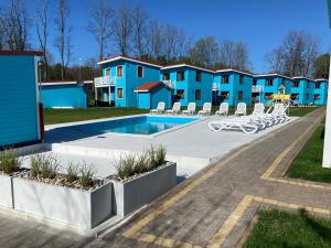 a resort with a swimming pool and some blue condos at Domki przy plaży Owocowy Ogród in Rewal