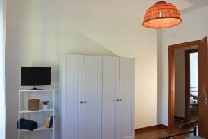 una camera con armadio bianco, TV e lampada di Dimidium Apartment a Guspini