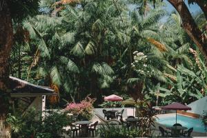 una piscina con mesas, sillas y palmeras en A Pousada da Praia, en São Luís