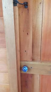 a wooden door with a blue button on the wall at La casita del bosque in Punta Indio