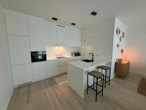 a kitchen with white cabinets and a counter and stools at Enjoy the Belgian coast with indoor heated swimmingpool and fitness in Ostend