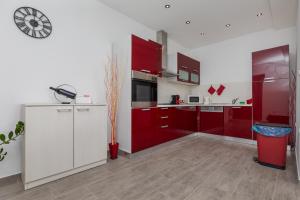 een keuken met rode kasten en een klok aan de muur bij Beach house Medići in Mimice