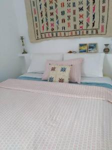 1 cama con edredón blanco y almohadas en Cosy House Tetouan's Old Medina Centre - La Casita en Zradna