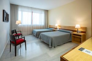 um quarto de hotel com duas camas e uma cadeira vermelha em Hospedería Mirador de Llerena em Llerena