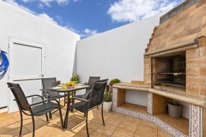 eine Terrasse mit einem Tisch und Stühlen sowie einem gemauerten Kamin in der Unterkunft Casa Carola in Arrecife