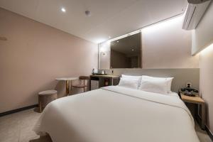 a bedroom with a large white bed and a mirror at Greaten Hotel in Seoul