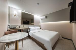 Cette chambre comprend un lit, une table et un miroir. dans l'établissement Greaten Hotel, à Séoul