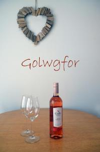 butelkę whisky i kieliszek wina na stole w obiekcie Golwgfor (Sea View) by Aberporth Beach Holidays w mieście Aberporth