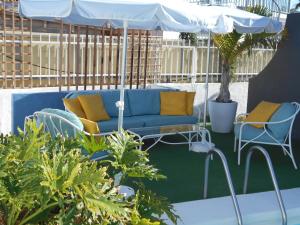 a blue couch and chairs under an umbrella on a patio at Beach Boys Resort Men Only solo hombres in Maspalomas