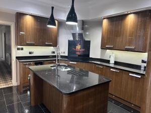 eine Küche mit Holzschränken und einer schwarzen Arbeitsplatte in der Unterkunft Third House Guest House in Aberdeen