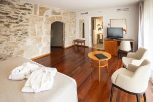 a living room with a bed and two chairs and a television at Hotel Puente de Alconétar in Garrovillas