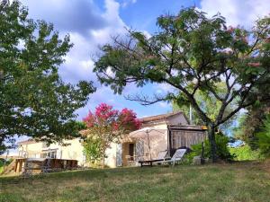 ein Haus mit einem Baum und einer Bank im Hof in der Unterkunft Home and pool between hamlet and forest garden in Saint-Méard-de-Gurçon