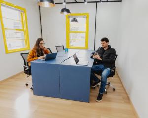 two people sitting at a desk in an office at Araucária Hostel in São Bento do Sul