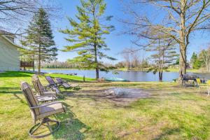 um grupo de bancos sentados na relva perto de um lago em Peaceful Lakefront Home with Deck in West Branch! em West Branch