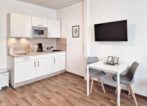 a kitchen with a white table and chairs and a tv at WO Apartments am Klinikum Wolfsburg in Wolfsburg