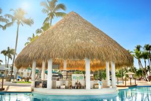 un bar junto a la piscina con sombrilla y palmeras en Sunscape Dominicus La Romana - All Inclusive, en La Romana