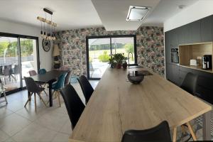 eine Küche und ein Esszimmer mit einem Holztisch und Stühlen in der Unterkunft Magnifique villa avec piscine à 20 min de hossegor in Saint-Geours-de-Maremne