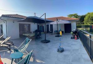 eine Terrasse mit Stühlen, einem Tisch und einem Sonnenschirm in der Unterkunft Magnifique villa avec piscine à 20 min de hossegor in Saint-Geours-de-Maremne