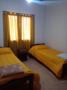a bedroom with two beds and a window with yellow sheets at La Soñada in Malargüe