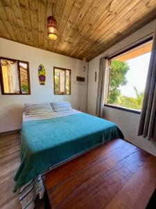 a bed in a room with a large window at Hospedagem Casa Maracujá in Trindade