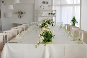 a long white table with glasses and flowers on it at Family Hotel Mania in Stara Zagora