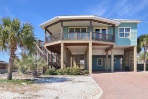 a large house with a balcony and palm trees at The Blue Turtle by Pristine Properties Vacation Rentals in Mexico Beach