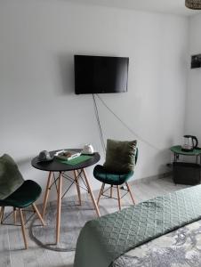 a living room with two chairs and a table and a tv at Le Manoir de la Pichardière in Cherrueix