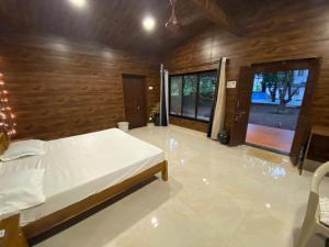 a bedroom with a white bed and a wooden wall at The Mango Woods Cottage with Bathtub in Alibag with Swimming Pool in Alibag