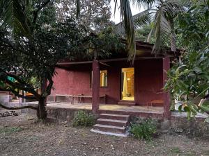 a red house with a yellow door and stairs outside at The Mango Woods Cottage with Bathtub in Alibag with Swimming Pool in Alibag