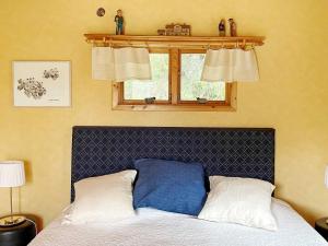 a bedroom with a bed with a blue headboard and a window at Holiday home GRÄSÖ II in Gräsö