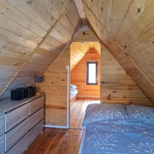 a bedroom with a bed in a wooden cabin at Arkadia Domki in Dziwnów