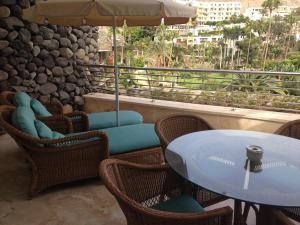 patio ze stołem, krzesłami i parasolem w obiekcie Anfi Beach Club 29 Jul a 04 Ago w mieście Las Palmas de Gran Canaria