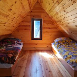 2 łóżka w drewnianym pokoju z oknem w obiekcie Arkadia Domki w Dziwnowie