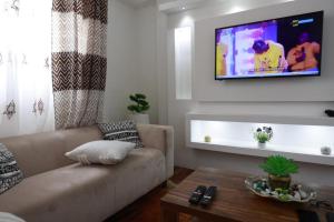 SERENITY Home في Spintex: غرفة معيشة مع أريكة وتلفزيون على الحائط