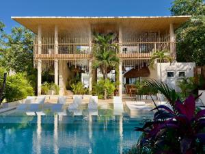 un complexe avec une piscine et des chaises blanches dans l'établissement Studios in Tulum by Casago, à Tulum
