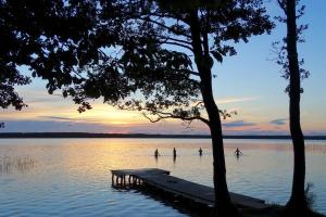 a group of people playing in a lake at sunset at Pirtiņa diviem in Ventspils