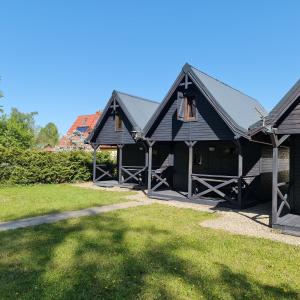 dom z czarnym dachem i ogródkiem w obiekcie Arkadia Domki w Dziwnowie