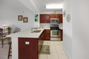 a kitchen with wooden cabinets and a stove top oven at Waterside Village Condo 302 by Pristine Properties Vacation Rentals in Mexico Beach